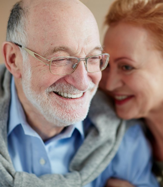 Older man and woman smiling after dental implant tooth replacement