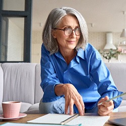 Woman in blue shirt smiling while working at home