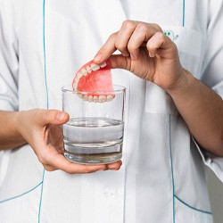 Patient putting denture in glass with water