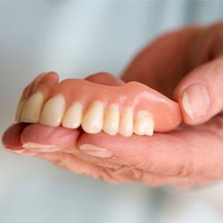 Close-up of hand holding dentures in Englewood, FL