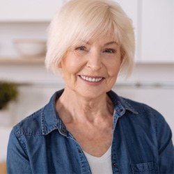 Woman in denim jacket standing in kitchen and smiling