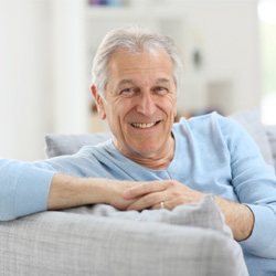 Senior man sitting on couch and smiling