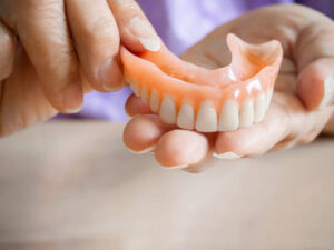 Close up of woman’s hands holding an upper denture